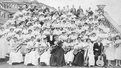 Large group of adult and teenage females posing with guitars